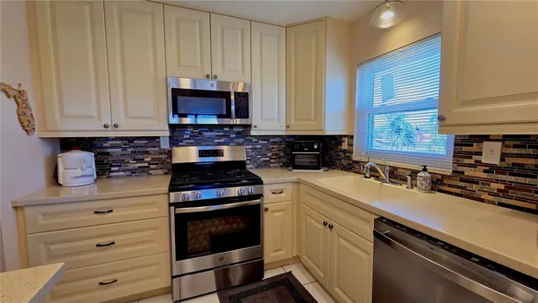 a kitchen with granite countertop a stove a sink and a microwave
