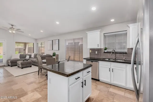 a kitchen with granite countertop a sink counter top space and living room view