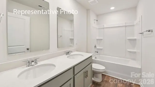 a bathroom with a granite countertop sink a toilet and shower