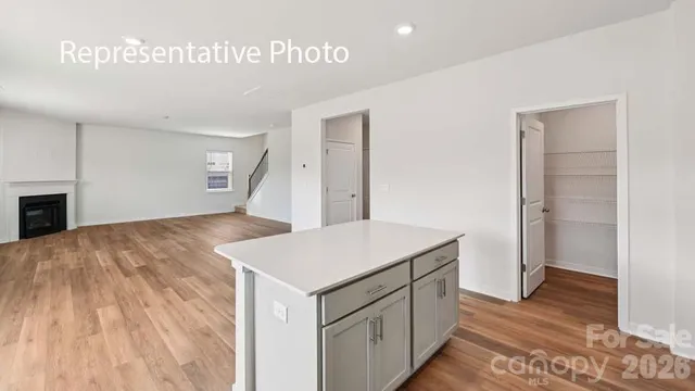 a hall with kitchen island white cabinets and wooden floor