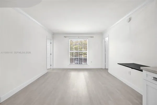 a view of an empty room with wooden floor and a window