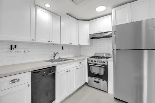 a kitchen with stainless steel appliances granite countertop a refrigerator stove a sink and dishwasher with white cabinets