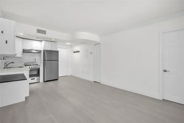 a view of a kitchen with a sink and dishwasher a refrigerator with white cabinets