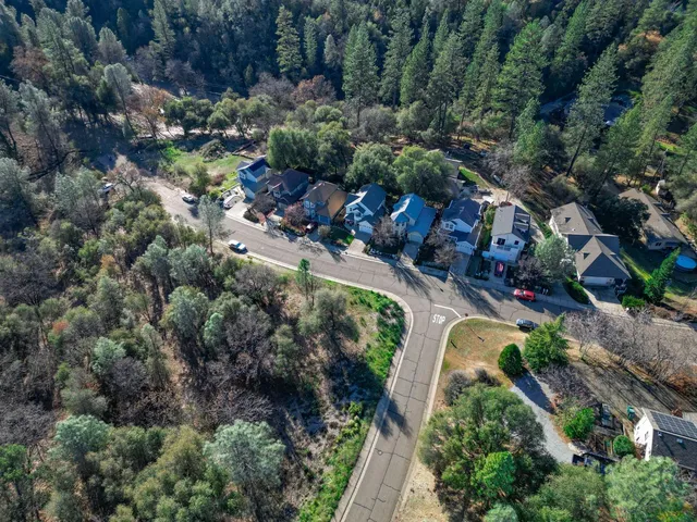 an aerial view of residential house with outdoor space and trees all around