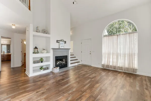a view of an empty room with chandelier fan and wooden floor