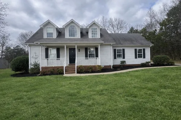 a view of a house with a big yard and large trees