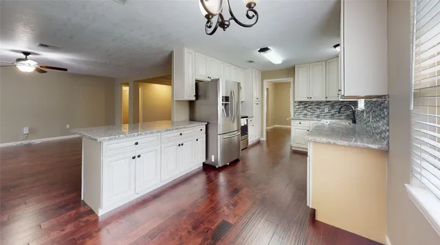 a large kitchen with a lot of counter space and wooden floor