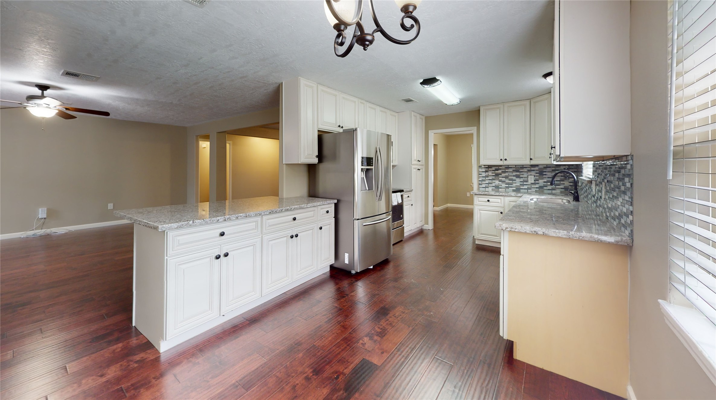 a large kitchen with a lot of counter space and wooden floor