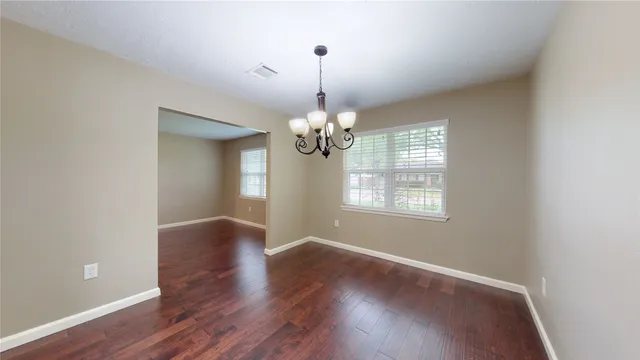 a view of an empty room with wooden floor and windows