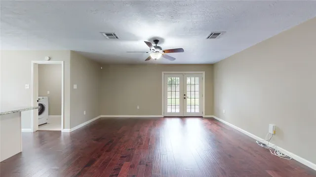 a view of an empty room with a window and wooden floor