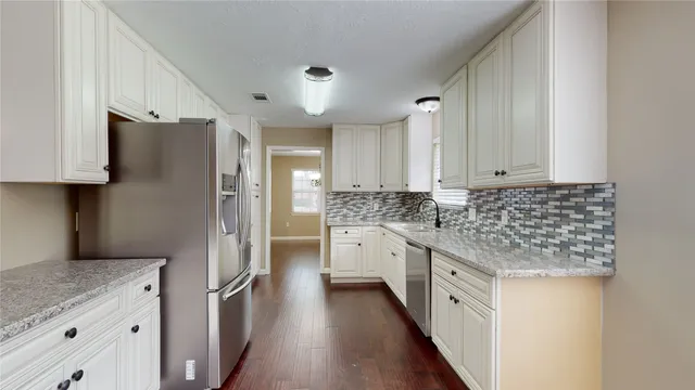 a kitchen with granite countertop white cabinets and stainless steel appliances