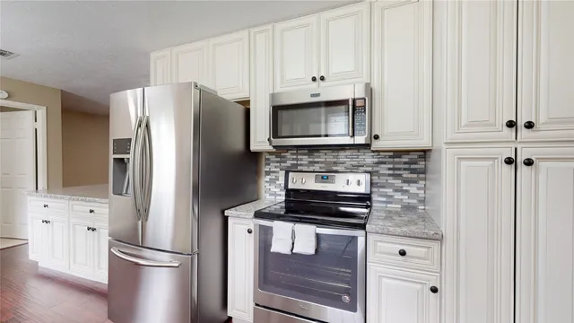 a kitchen with appliances a refrigerator and cabinets