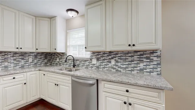 a kitchen with stainless steel appliances granite countertop white cabinets and a sink