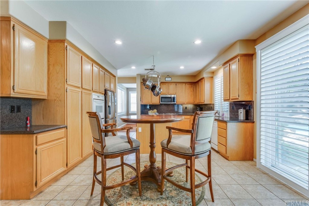 23537 Cantara Road Corona, CA 92883 - Photo 23 of 60 a kitchen with kitchen island a table and chairs in it