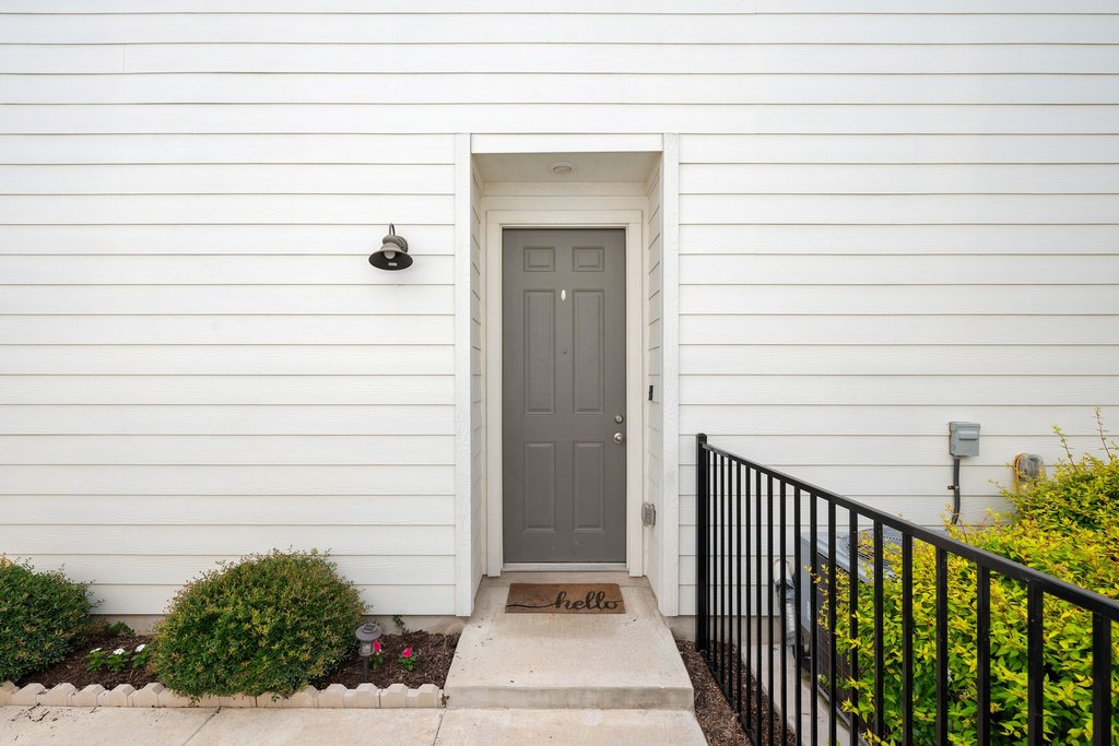 7403 Travertine Spring Drive, Unit 117 Austin, TX 78744 - Photo 8 of 37 A welcoming front entrance featuring a panel door and a practical handrail, framed by verdant shrubs.