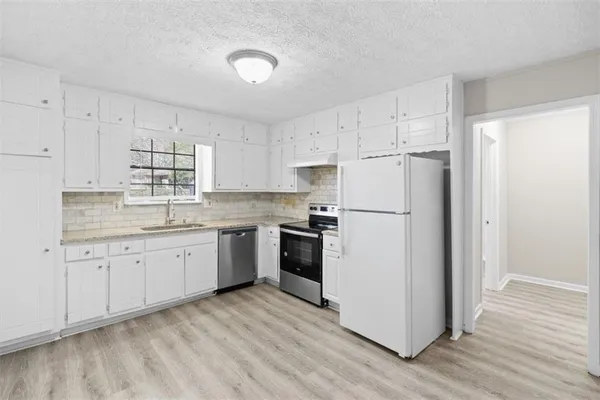 a kitchen with cabinets stainless steel appliances and wooden floor