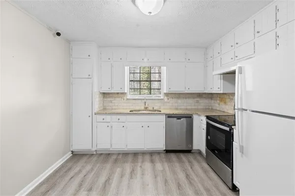 a kitchen with granite countertop white cabinets and white appliances