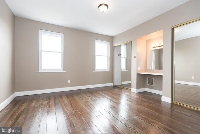 an empty room with wooden floor and windows