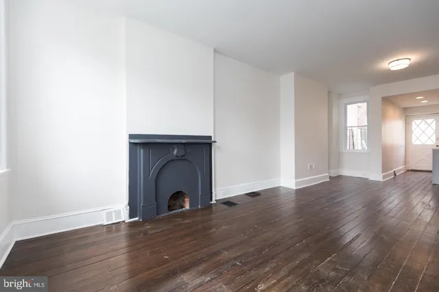 a view of a livingroom with wooden floor and a fireplace