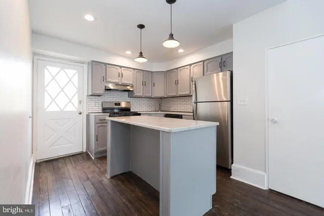 a kitchen with stainless steel appliances granite countertop a refrigerator a sink dishwasher a stove and white countertops with wooden floor