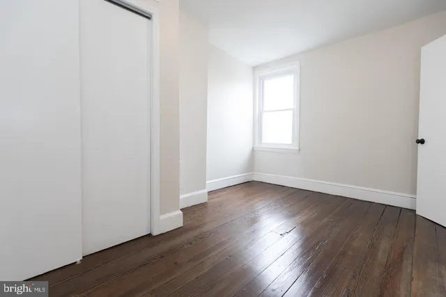 an empty room with wooden floor and window