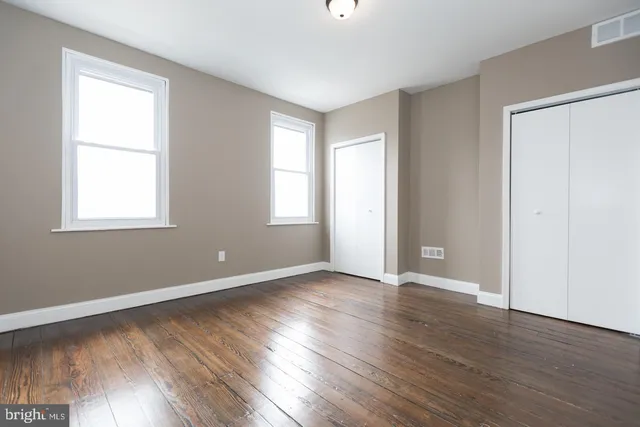an empty room with wooden floor and windows