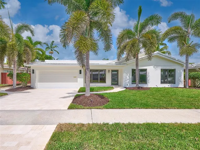 a front view of a house with a garden and trees