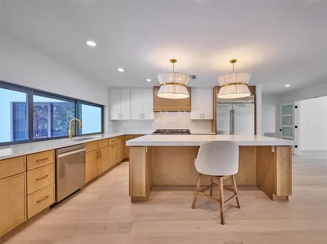 a kitchen with white cabinets and a large window