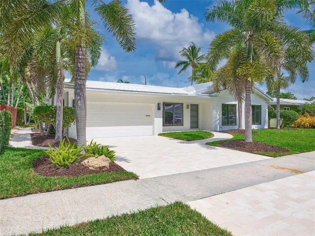 a view of a house with a yard and palm trees