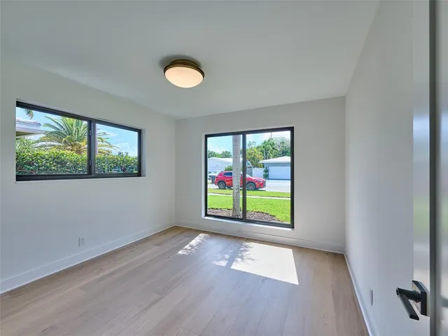 a view of an empty room with a window and wooden floor