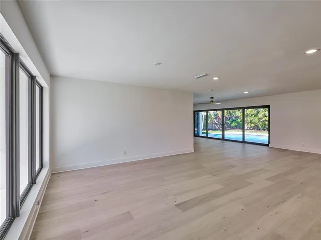 a view of an empty room with a window and wooden floor