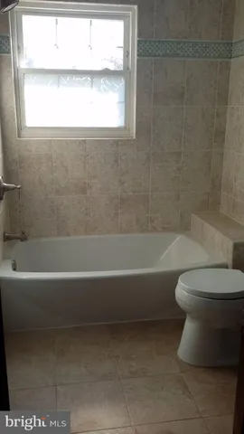 a bathroom with a toilet bathtub and window