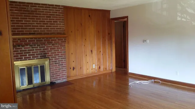 a view of an empty room with wooden floor and a fireplace