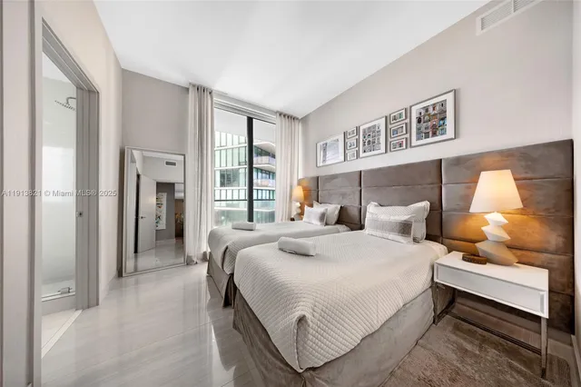 a bedroom with a bed and a lamp on dresser with wooden floor