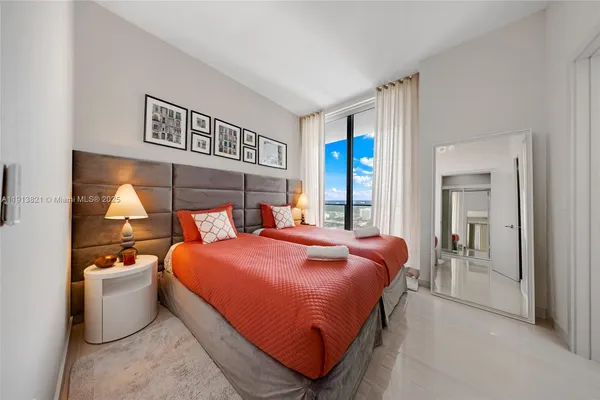 a bedroom with a large bed and a flat tv screen next to a window