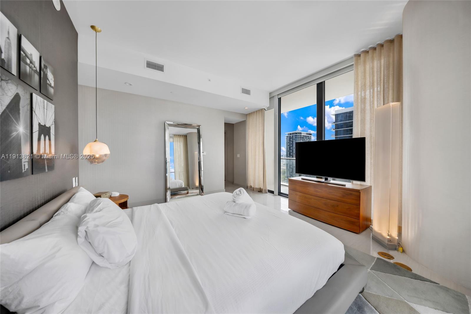 480 Northeast 31st Street, Unit 2807 Miami, FL 33137 - Photo 24 of 45 a bedroom with a bed and a flat screen tv