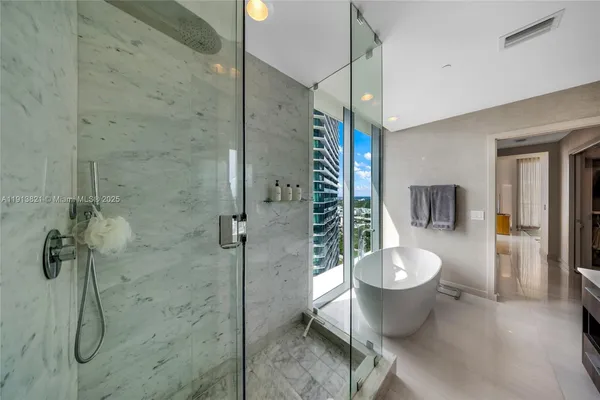 a bathroom with a double vanity sink a large mirror and a bathtub
