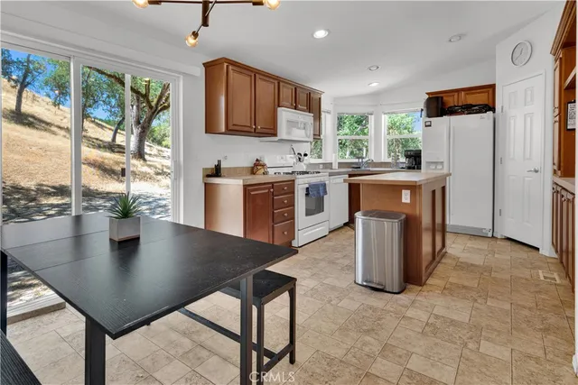 a kitchen with stainless steel appliances granite countertop a stove a refrigerator a kitchen island a stove a dining table and chairs with the view of kitchen