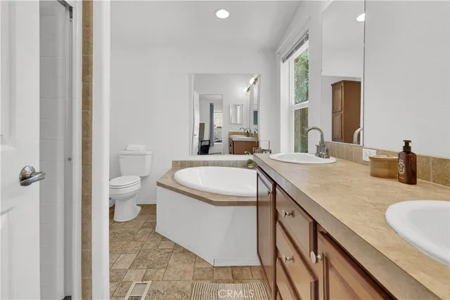 a bathroom with a granite countertop sink a toilet and a tub