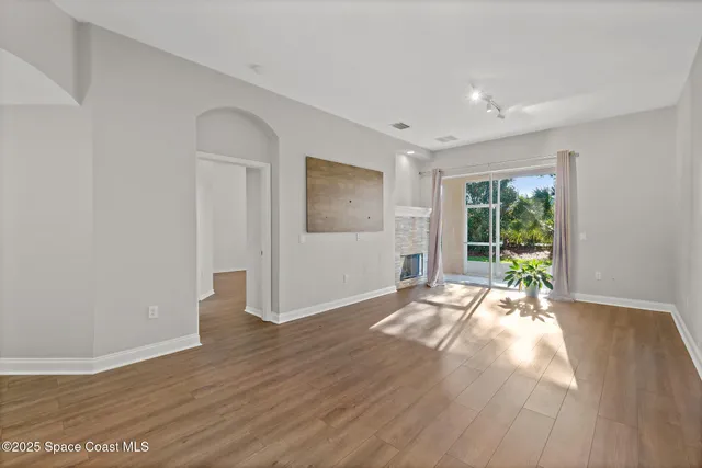 a view of an empty room with wooden floor and a window