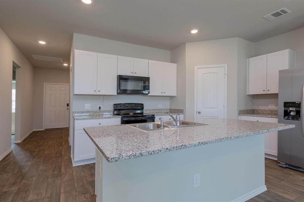 6009 Ronee Leah Drive Austin, TX 78724 - Photo 7 of 16 A well-appointed kitchen features a central island, granite countertops, and modern appliances.