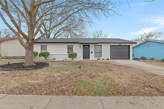 a view of a house with a yard and large tree