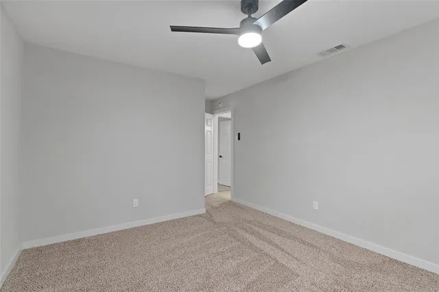an empty room with a ceiling fan and a window