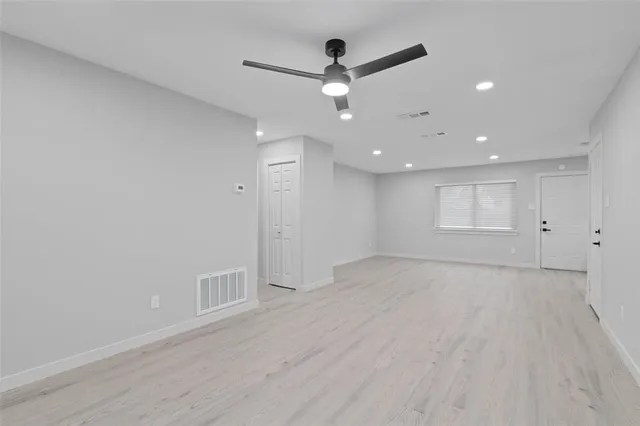 an empty room with wooden floor and a ceiling fan
