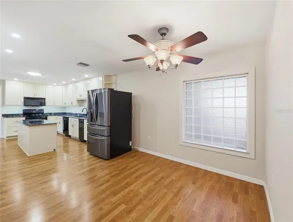 a view of kitchen with stainless steel appliances kitchen island granite countertop a refrigerator oven a stove top oven with a dining table and chairs with wooden floor