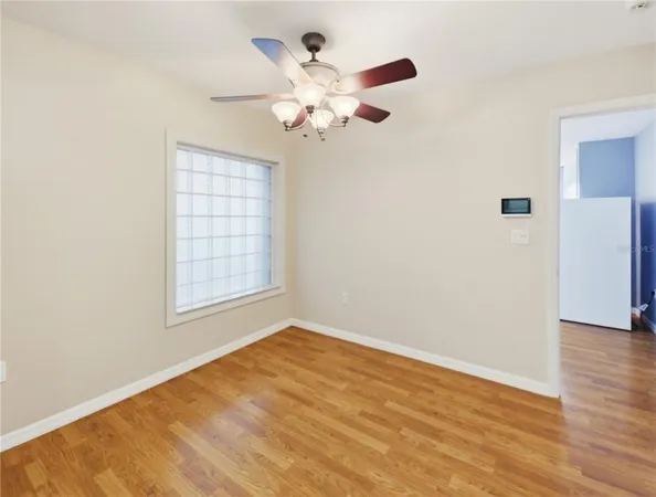 an empty room with wooden floor fan and windows