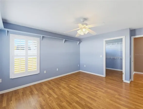 a view of an empty room with a window and wooden floor
