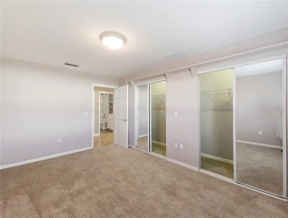 an empty room with closet and windows