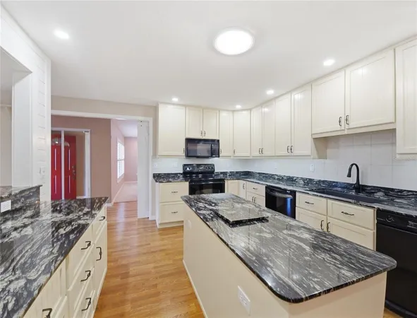 a kitchen with stainless steel appliances granite countertop a stove top oven a sink and dishwasher a refrigerator with wooden floor