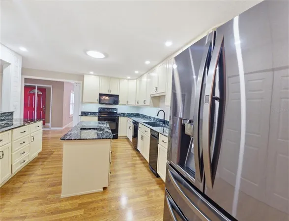 a large kitchen with stainless steel appliances granite countertop a refrigerator and a stove
